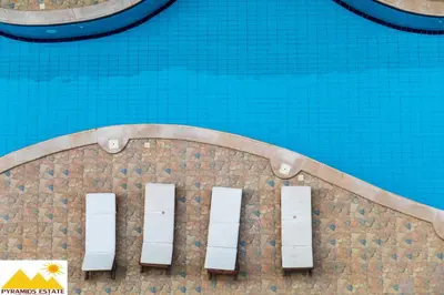 a swimming pool with blue water and white doors at Nour Plaza Hurghada Studio Sea view in Hurghada