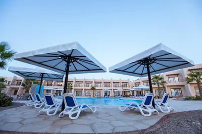 a group of chairs and umbrellas next to a pool at Sky View Suites Hotel in Hurghada