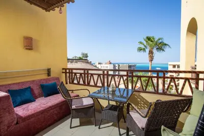 a balcony with a couch and chairs and the ocean at The View Apartment in Hurghada
