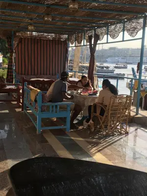 a group of people sitting at a table in a restaurant at Awi Guest House in Aswan