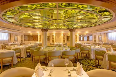 a restaurant with white tables and chairs and a large ceiling at Sonesta St George Nile Cruise - Aswan to Luxor 3 Nights from Friday to Monday in Aswan