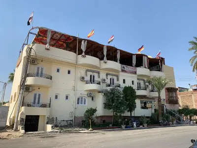 a large white building with flags on top of it at Nile Valley Hotel in Luxor