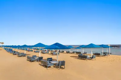 a row of chairs and umbrellas on a beach at Pickalbatros Sea World Resort - Marsa Alam- 