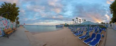 a beach with blue lounge chairs and the ocean at MinaMark Beach Resort for Families and Couples Only in Hurghada