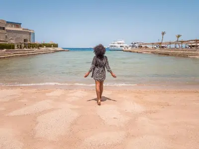 a woman walking on the beach near the water at Seagull Beach Resort - Families and Couples Only in Hurghada