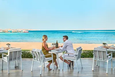 a man and woman sitting at a table on the beach at Steigenberger Pure Lifestyle (Adults Only) in Hurghada