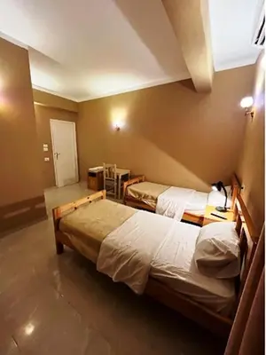 a bedroom with two beds and a table with a desk at Kareem Hotel Luxor in Luxor