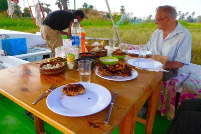 a man sitting at a table with plates of food at Villa Sunrise in Luxor