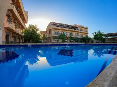 a pool of blue water in front of a building at New Memnon Hotel in Luxor
