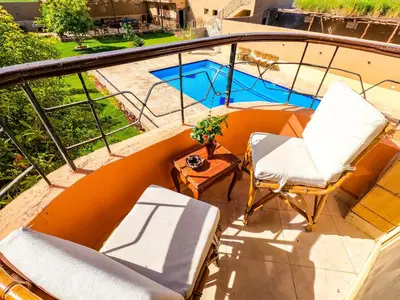 a balcony with chairs and a table and a pool at New Memnon Hotel in Luxor