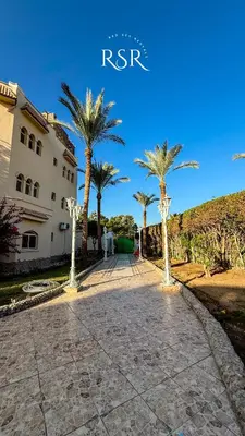 a walkway with palm trees in front of a building at Green Garden Resort in Hurghada