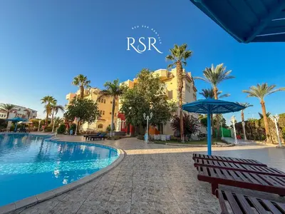 a resort with a swimming pool and a blue umbrella at Green Garden Resort in Hurghada