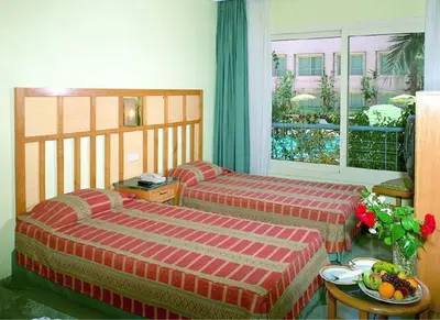 a bedroom with two beds and a table with a bowl of fruit at Sea Garden Hotel in Hurghada