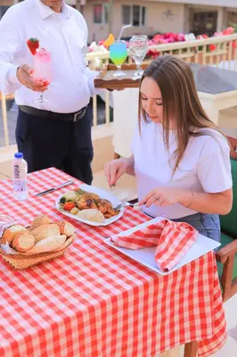 a woman sitting at a table with a plate of food at Sea Star Beau Rivage Hotel in Hurghada