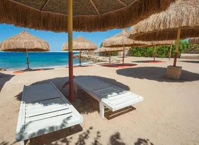 a beach with chairs and umbrellas on the sand at Sun & Sea Hotel and Aqua Park - Hurghada in Hurghada