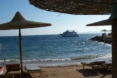 a boat in the ocean with chairs and an umbrella at Sun & Sea Hotel and Aqua Park - Hurghada in Hurghada