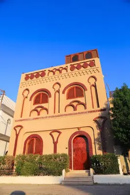 a tall building with a red door and windows at Shahhat House in Luxor