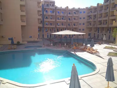 a large swimming pool in front of a building at Tiba Resort Hurghada in Hurghada