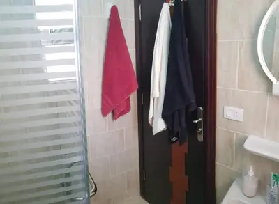 a bathroom with a shower and towels hanging on the door at Tiba Resort Hurghada in Hurghada