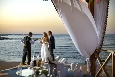 a bride and groom drinking at their wedding on the beach at Concorde Moreen Beach Resort in Abu Dabab