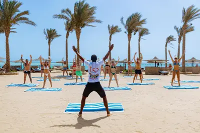 a group of people doing yoga on the beach at Blend Elphistone Resort Marsa Alam in Abu Dabab
