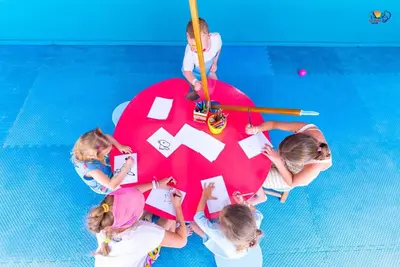 a group of children sitting around a table with paper at Ali Baba Palace Resort in Hurghada