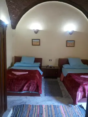 a room with two beds and a room with two tables at Maghrabi's Guest house in Aswan