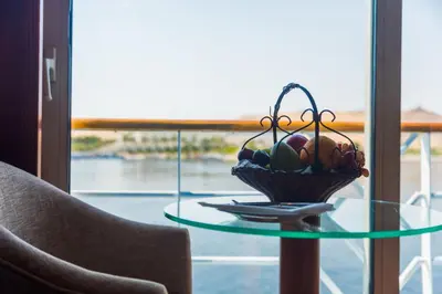 a basket of fruit on a glass table next to a window at Nile Cruise King Tut in Luxor