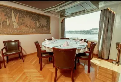 a dining room with a table and chairs and a large window at Nile Cruise King Tut in Luxor