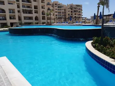 a swimming pool with blue water in front of a building at Aldau Heights in Hurghada