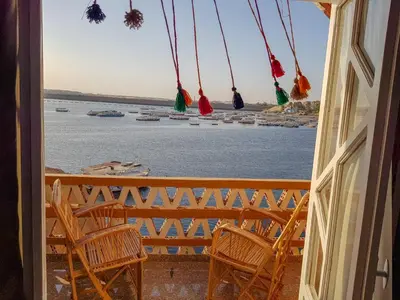 a balcony with chairs and a view of the water at Old Nubian guest house in Aswan