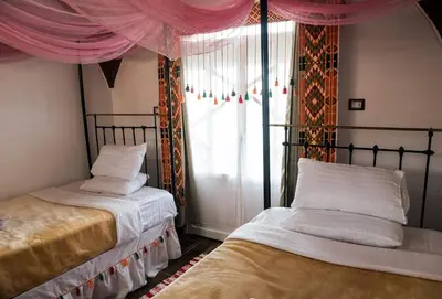 a bedroom with two beds and a window with pink curtains at Old Nubian guest house in Aswan