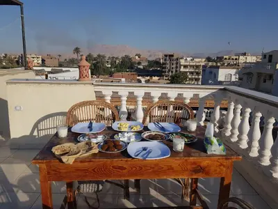 a table with plates of food on a balcony at Nile Sunrise Flats And Rooms in Luxor