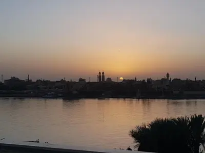 a sunset over a body of water with a city at Nile Sunrise Flats And Rooms in Luxor