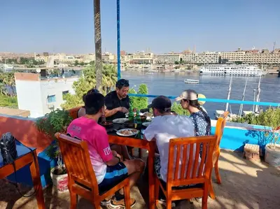 a group of people sitting around a table eating food at Bob Marley Guest House in Aswan