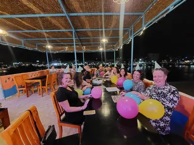 a group of people sitting at a table with balloons at Bob Marley Guest House in Aswan