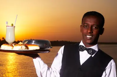 a man holding a plate of food and a drink at Nile Carnival Cruise 4nt Lxr Thursday 3nt Asw Monday in Luxor