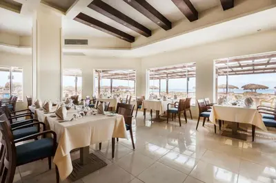 a dining room with tables and chairs and windows at Shams Lodge in Hurghada