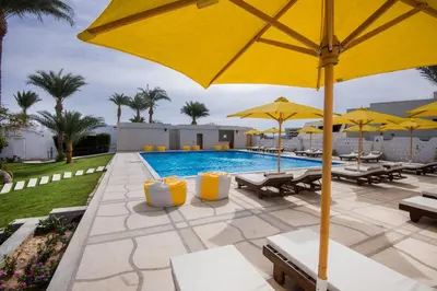 a pool with yellow umbrellas and tables and chairs at Shams Lodge in Hurghada