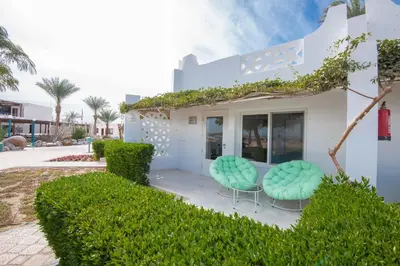 a white house with two green chairs on a patio at Shams Lodge in Hurghada