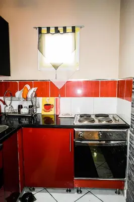 a kitchen with red cabinets and a stove top oven at Desert Pearl Art in Hurghada