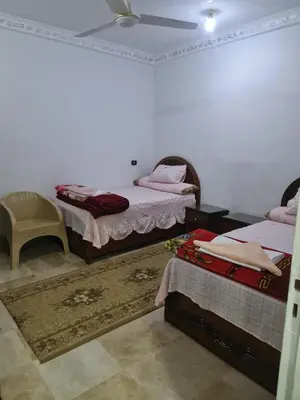 a bedroom with two twin beds and a chair at The Green Nubian House in Aswan