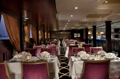 a restaurant with white tables and purple chairs at Steigenberger Minerva Nile Cruise - Every Thursday from Luxor for 07 & 04 Nights - Every Monday From Aswan for 03 Nights in Luxor