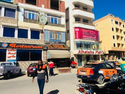 a man walking down a street in a city at Karibu House Sheraton Road in Hurghada