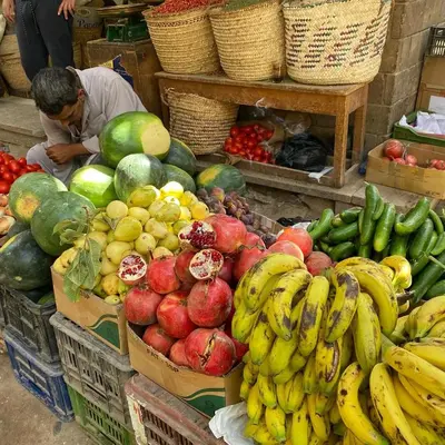 a man sitting in front of a display of fruits and vegetables at Karibu House Sheraton Road in Hurghada
