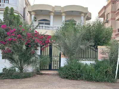 a house with a black gate and pink flowers at Soliman Nile View in Luxor
