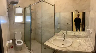 a man taking a picture of a bathroom with a sink and shower at Bahga Palace 1 Residential Apartments in Hurghada