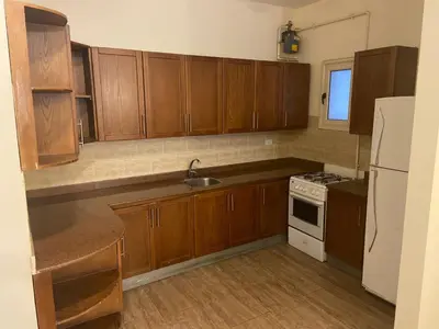 a kitchen with wooden cabinets and a white refrigerator at Bahga Palace 2 Residential Apartments in Hurghada