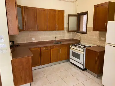 a kitchen with wooden cabinets and a stove top oven at Bahga Palace 3 Residential Apartments in Hurghada