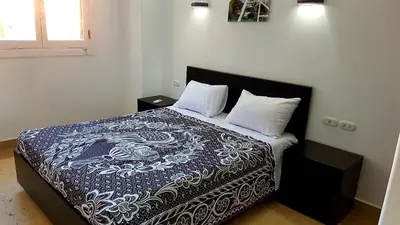 a bed with a blue and white blanket and two pillows at Apartments in Almaz Plaza in Hurghada